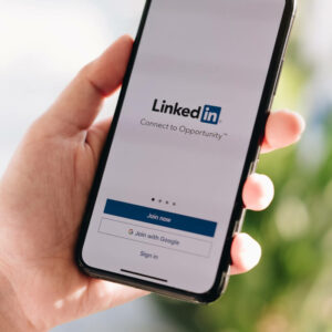 Osoba trzymająca w dłoni telefon z logo aplikacji LinkedIn na ekranie