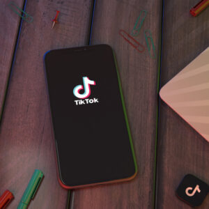 Stół, na którym jest położony telefon z włączoną aplikacją TikTok.