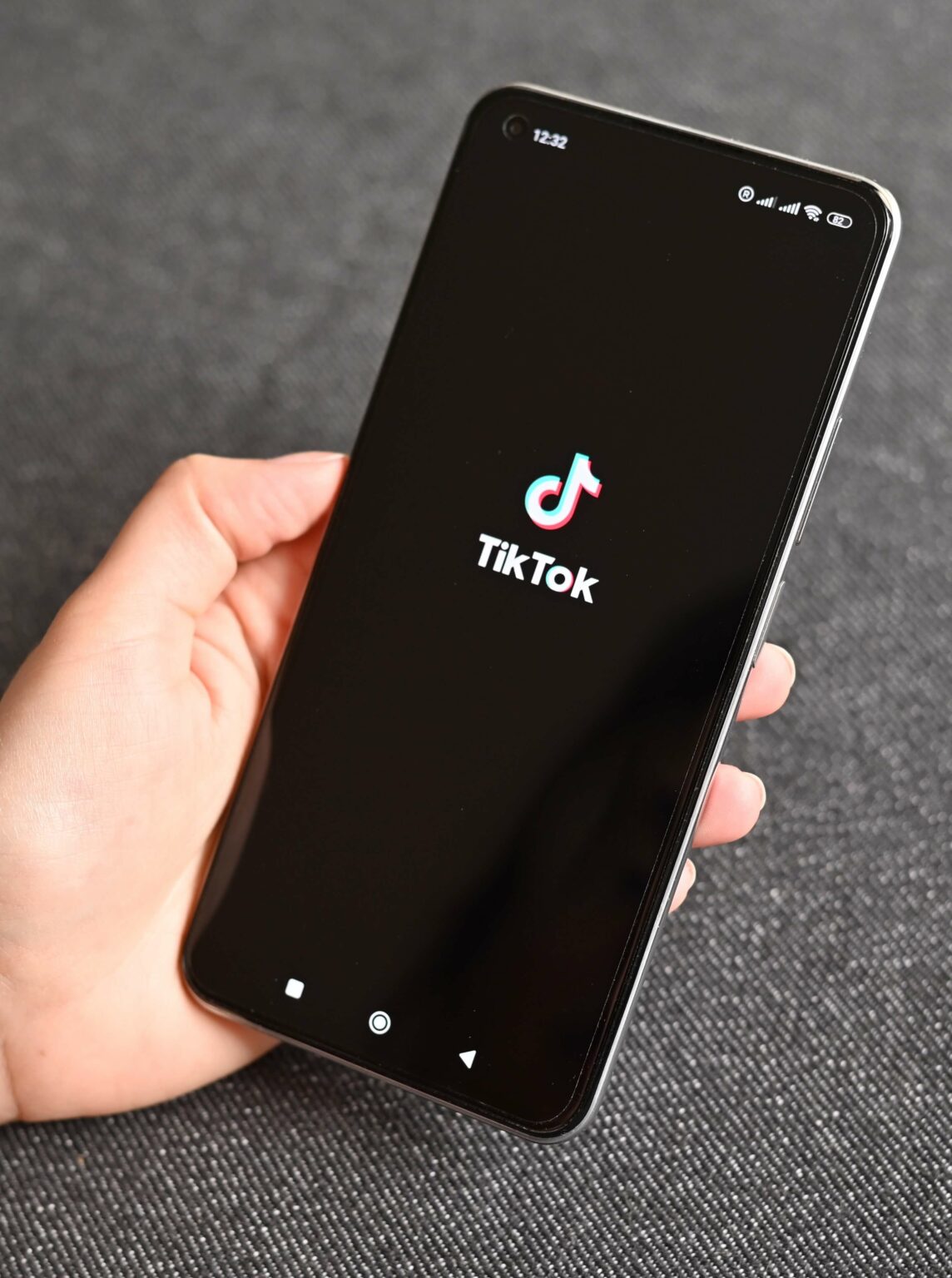 Telefon z logo TikToka, trzymany w dłoni.