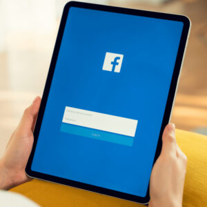 Osoba logująca się do Facebooka na tablecie.