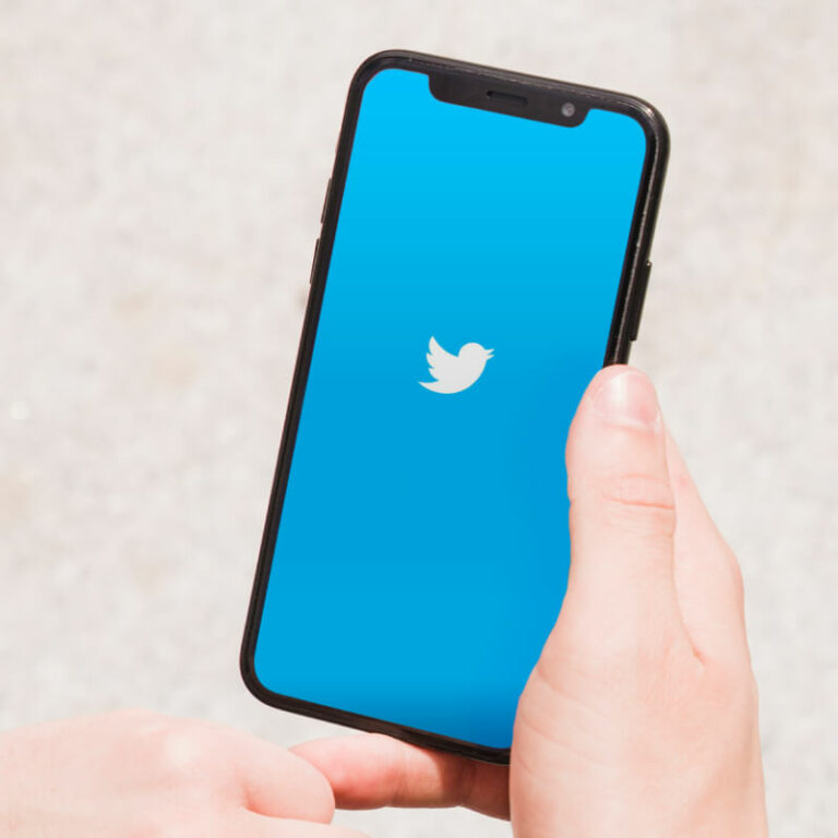 Osoba, trzymająca ręce telefon z logo Twittera.