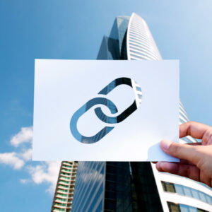 Osoba trzymająca kartkę z symbolem linku na tle budynku