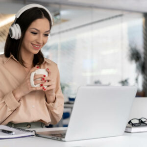 Osoba siedząca przy laptopie w słuchawkach