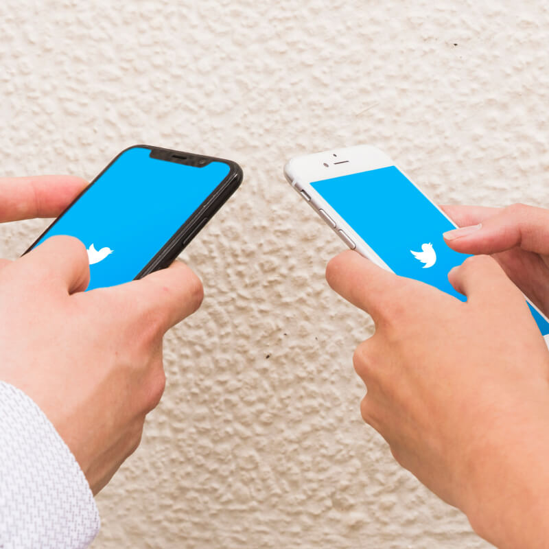 Dwie osoby trzymające telefony z włączoną aplikacją Twitter.