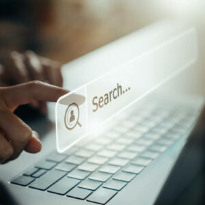 Ręka dotykająca okna wyszukiwania na tle laptopa