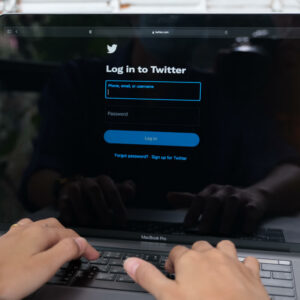 Osoba logująca się do Twittera na laptopie.