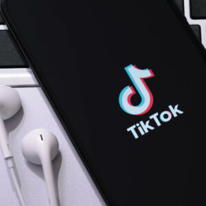 Telefon i słuchawki położone na laptopie.