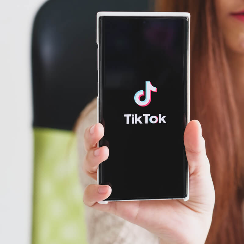 Telefon z logo TikToka trzymany w dłoni