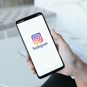 Telefon z logo Instagrama, trzymany w ręce, na białym tle