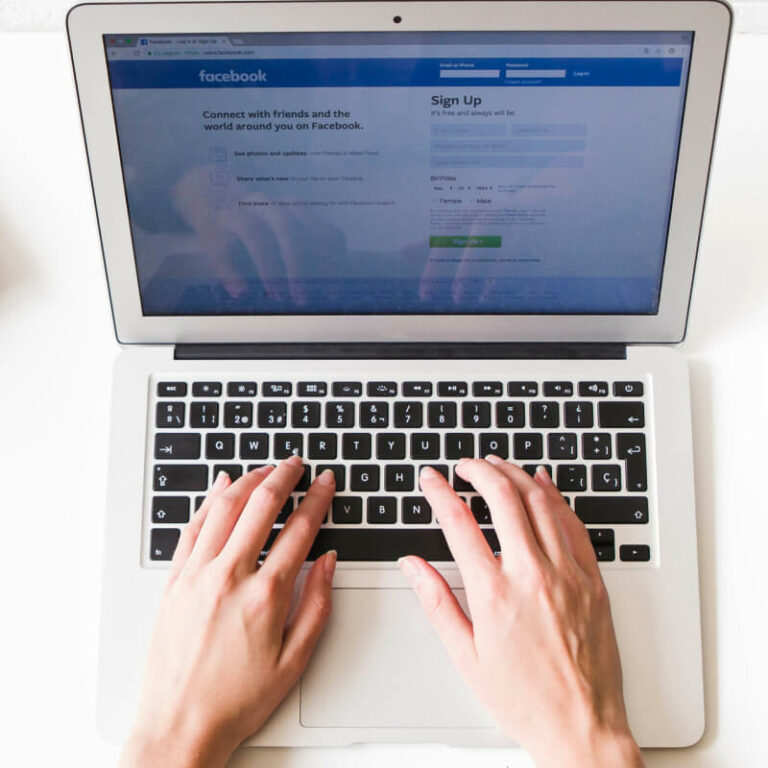 Osoba logująca się do Facebooka na laptopie.