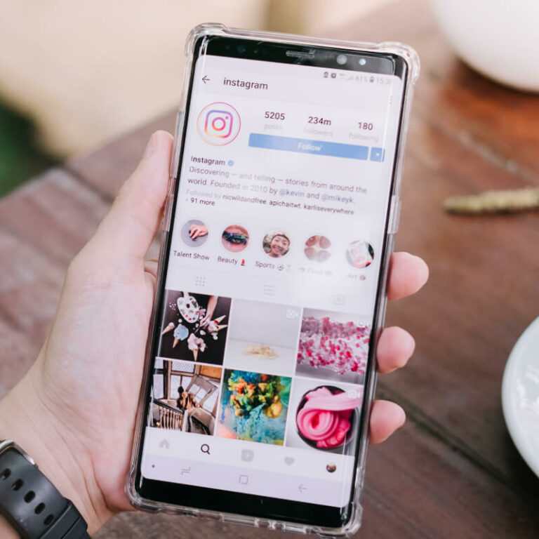 Telefon z wyświetlonym profilem na Instagramie, trzymany w ręce.