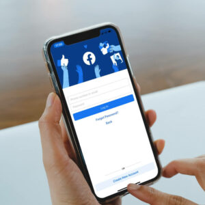 Osoba logująca się do Facebooka za pomocą telefonu.