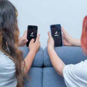Dwie osoby trzymające telefony z logo TikToka