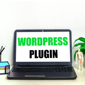 Laptop z napisem WordPress, stojący na biurku obok dekoracji.