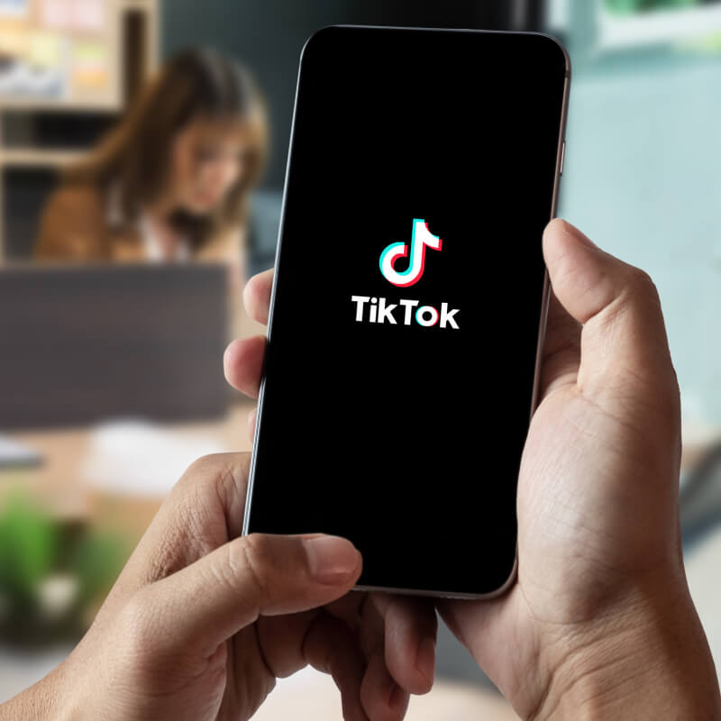 Telefon z logo TikToka, trzymany w dłoniach