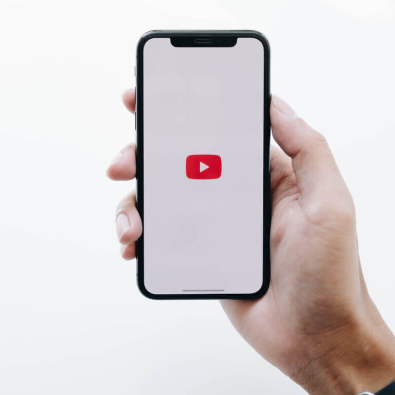 Telefon z logo YouTube trzymany w ręce.
