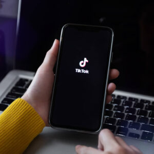 Telefon z logo TikToka na tle laptopa