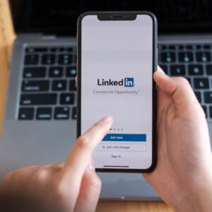 Telefon z ekranem logowania do LinkedIn na tle klawiatury laptopa