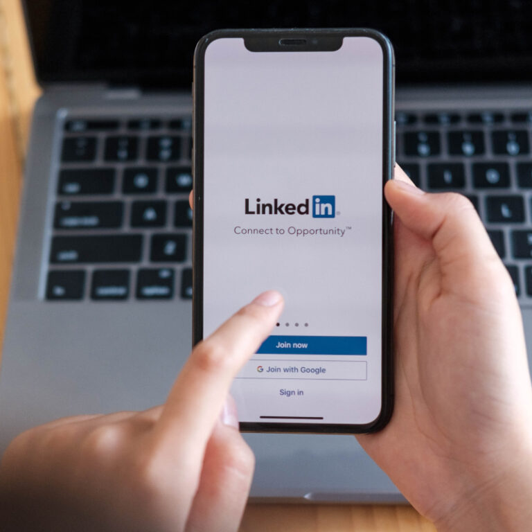 Telefon z ekranem logowania do LinkedIn na tle klawiatury laptopa