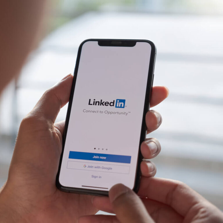 Osoba trzymająca telefon z ekranem logowania do LinkedIn