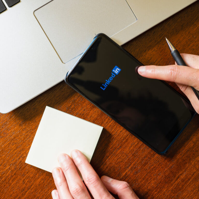 Osoba z długopisem i kartką, przeglądająca LinkedIn