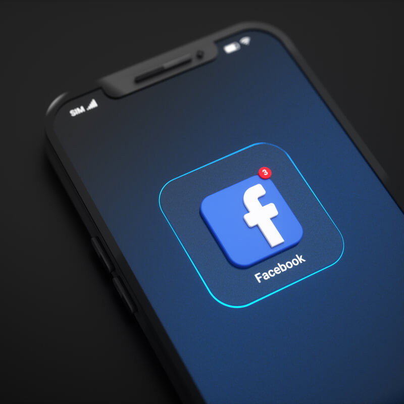 Telefon z logo Facebooka, na ciemnym tle