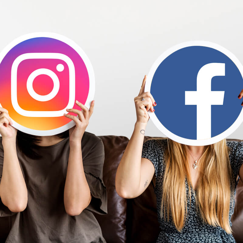 Dwie osoby trzymające logo Instagrama i Facebooka