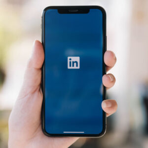 Osoba, trzymająca telefon z logo LinkedIn