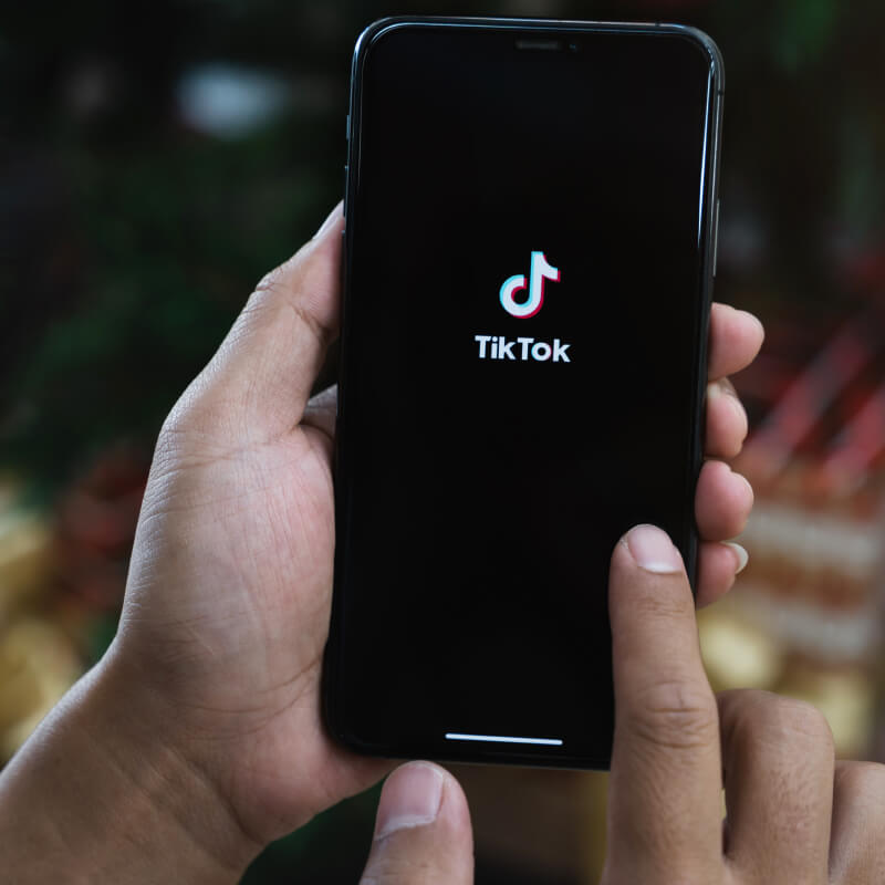 Osoba trzymająca telefon z logo TikToka