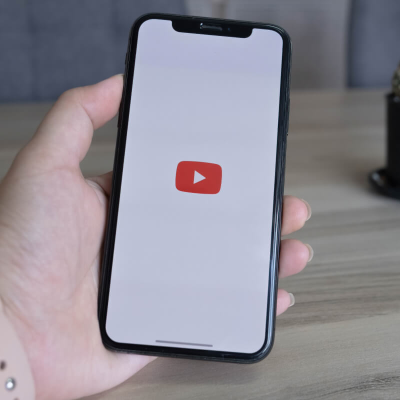 Osoba trzymająca telefon z logo YouTube