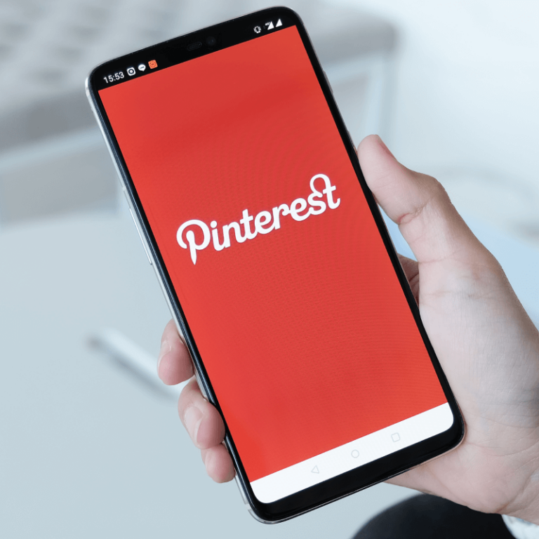 Osoba trzymająca w dłoni telefon z logo Pinteresta
