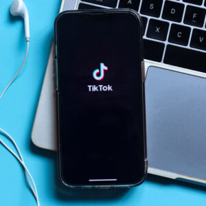 Telefon z logo TikToka na tle laptopa.