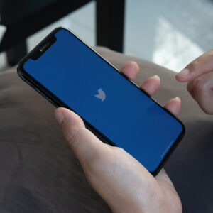 Osoba trzymająca w dłoni telefon z logo Twittera na ekranie