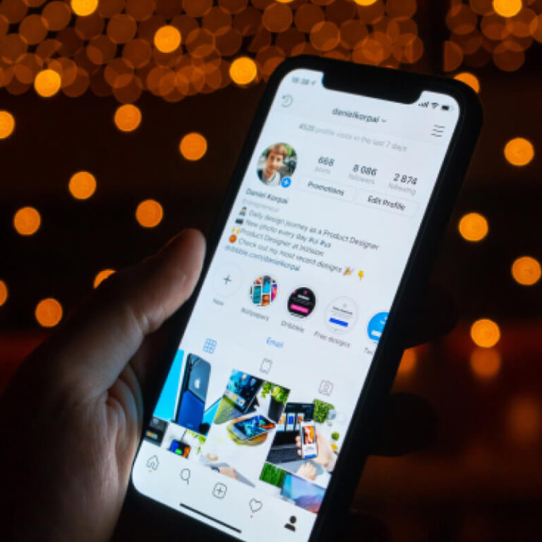 Telefon wyświetlający bio profilu w aplikacji Instagram na tle żółtych lampek