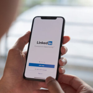 Osoba trzymająca w dłoniach smartfon z ekranem logowania do LinkedIn