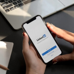 Osoba trzymająca w dłoniach telefon z ekranem logowania do LinkedIn