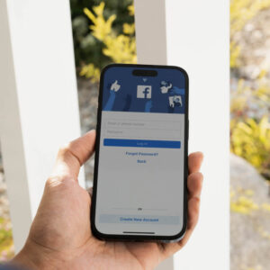 Telefon z ekraniem logowania do aplikacji Facebook trzymany w dłoni