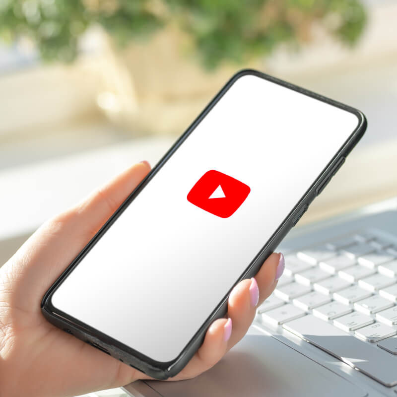 Telefon z logo YouTube trzymany w dłoni.
