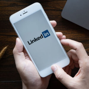 Osoba trzymająca w dłoniach telefon z logo LinkedIn na ekranie