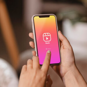 Osoba trzymająca w dłoniach telefon z Logo Rolek z aplikacji Instagram