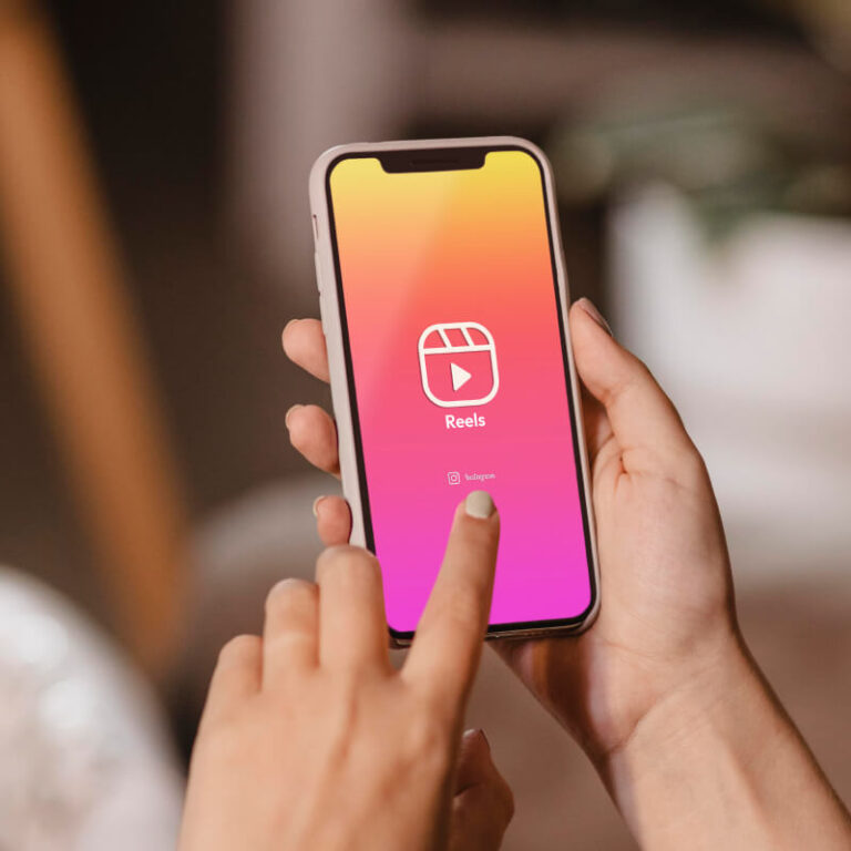 Osoba trzymająca w dłoniach telefon z Logo Rolek z aplikacji Instagram