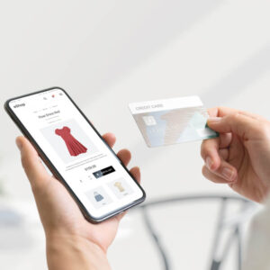 Osoba dokonująca zakupów online, trzymająca w dłoni telefon i kartę kredytową
