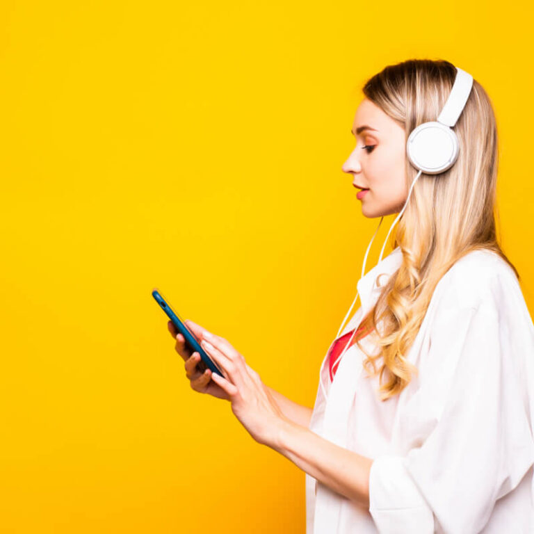 Osoba z pokolenia Gen Z słuchająca mizyki przez słuchawki na żółtym tle