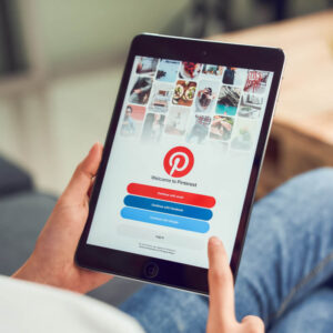 Osoba trzymająca w dłoniach tablet z ekranem logowania do aplikacji Pinterest