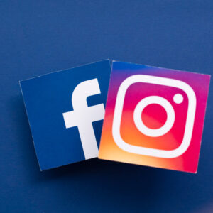 Logo aplikacji Facebook i Instagram koncernu Meta na niebieskim tle