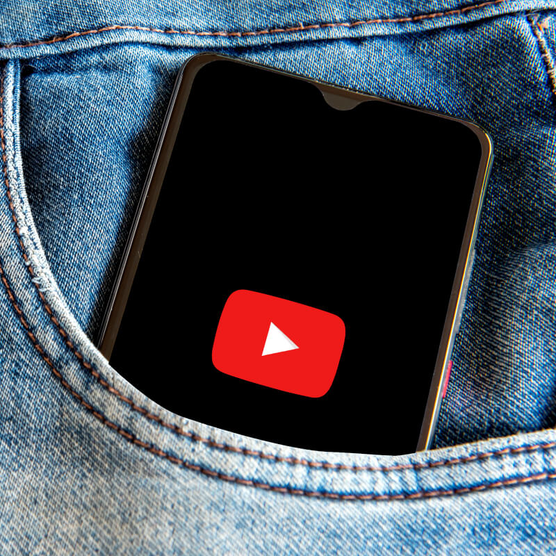 Telefon z logo YouTube umieszczony w kieszeni spodni