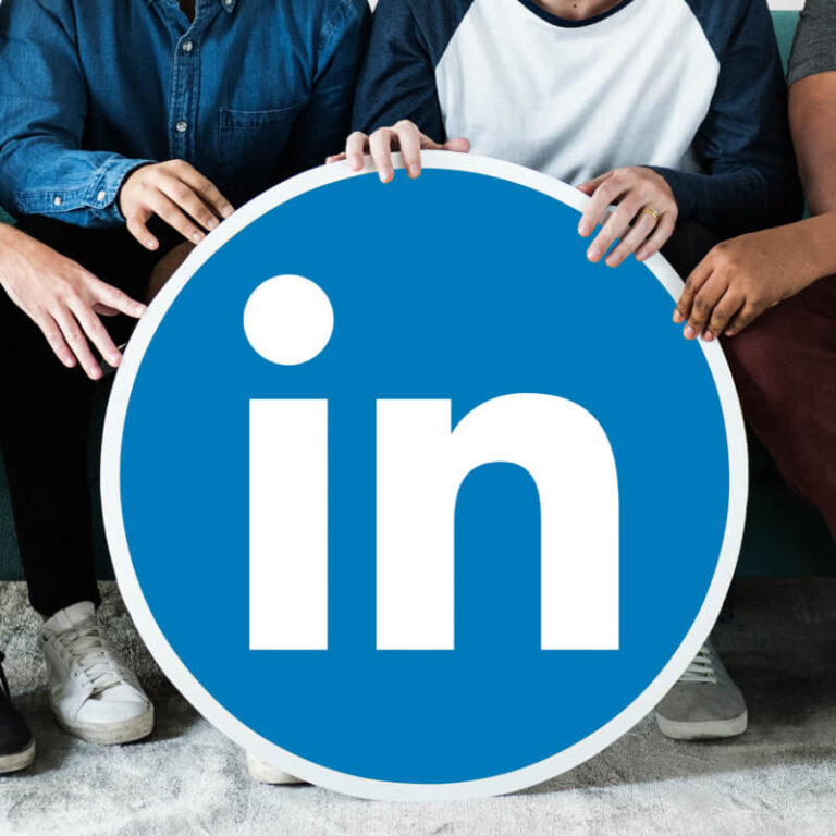 Okrągłe logo LinkedIn trzymane w dłoniach przez grupę osób