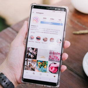 Osoba trzymająca w dłoni telefon z wyświetlonym proflem na Instagramie