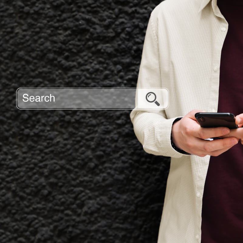 Osoba trzymająca w dłoniach telefon, z paskiem wyszukiwania Google na czarnym tle