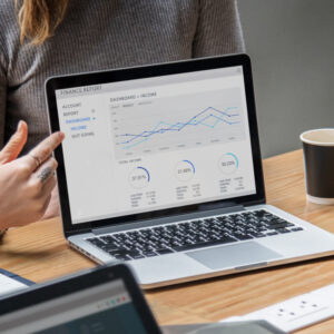 Laptop z wykresami na ekranie stojący na biurku